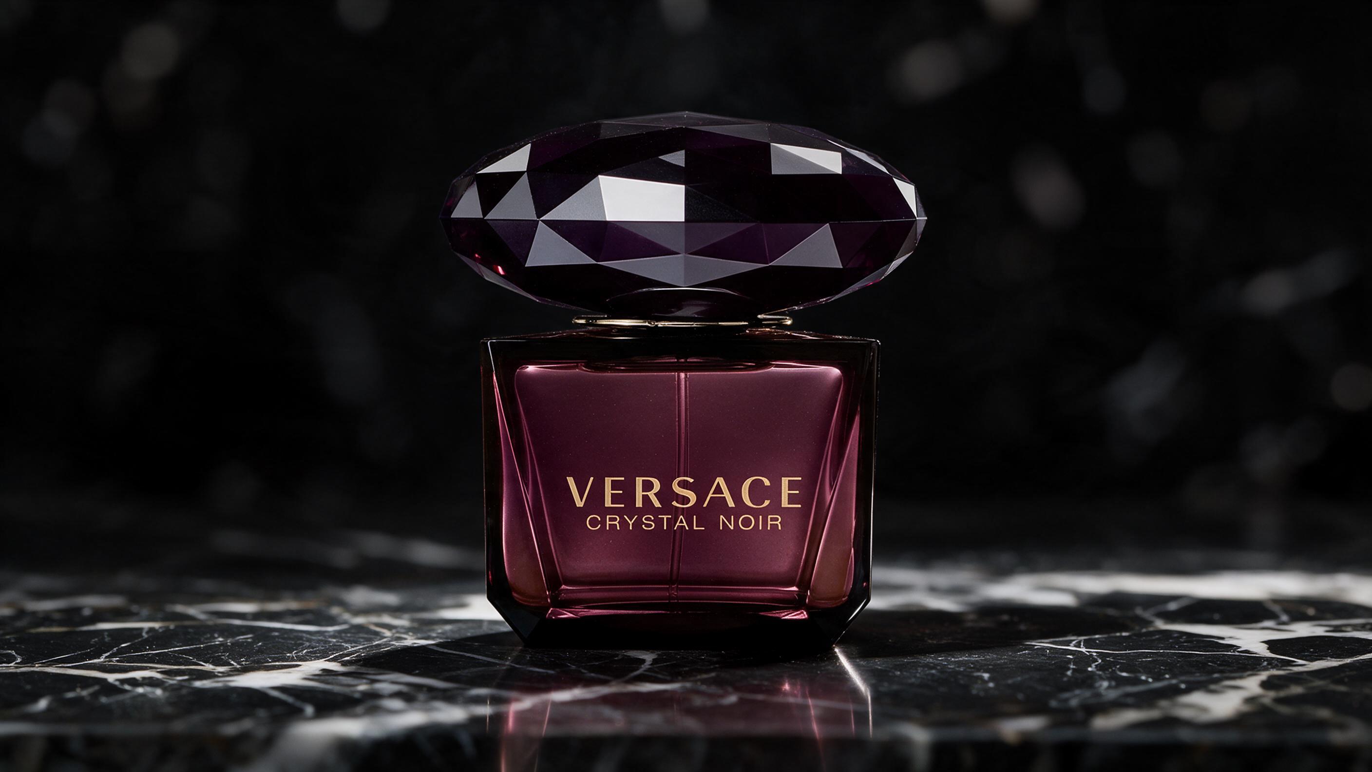 elegant dark plum and black faceted crystal perfume bottle with sleek black cap, standing on dark marble surface, dramat