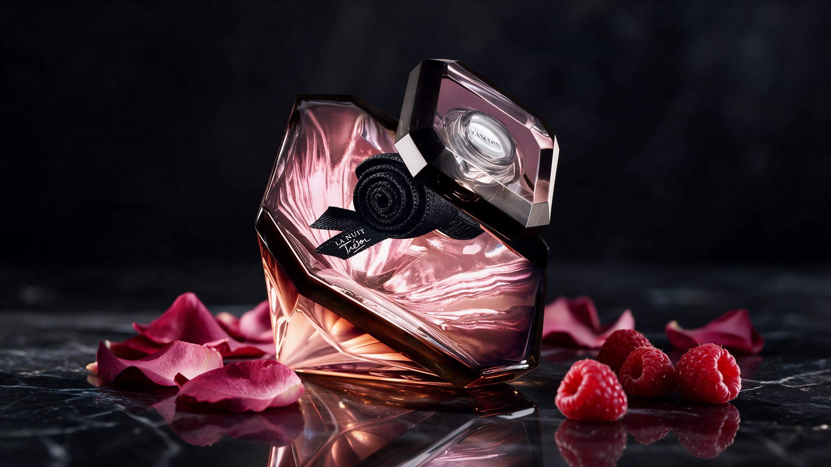 elegant perfume bottle of a dark amber-pink gradient glass with a faceted ruby-red cap, standing on a dark reflective su
