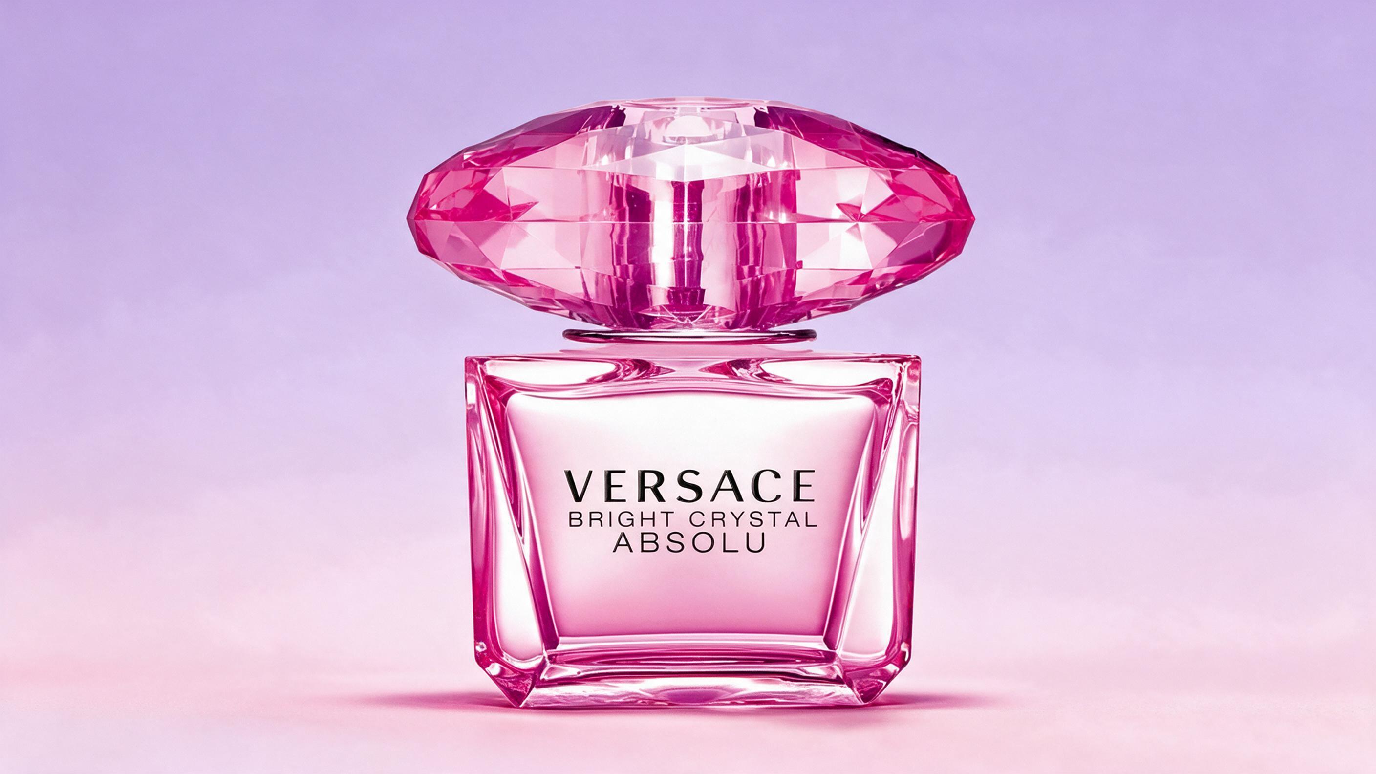 professional studio product photography of an elegant faceted crystal-clear perfume bottle with a round pink gemstone-st