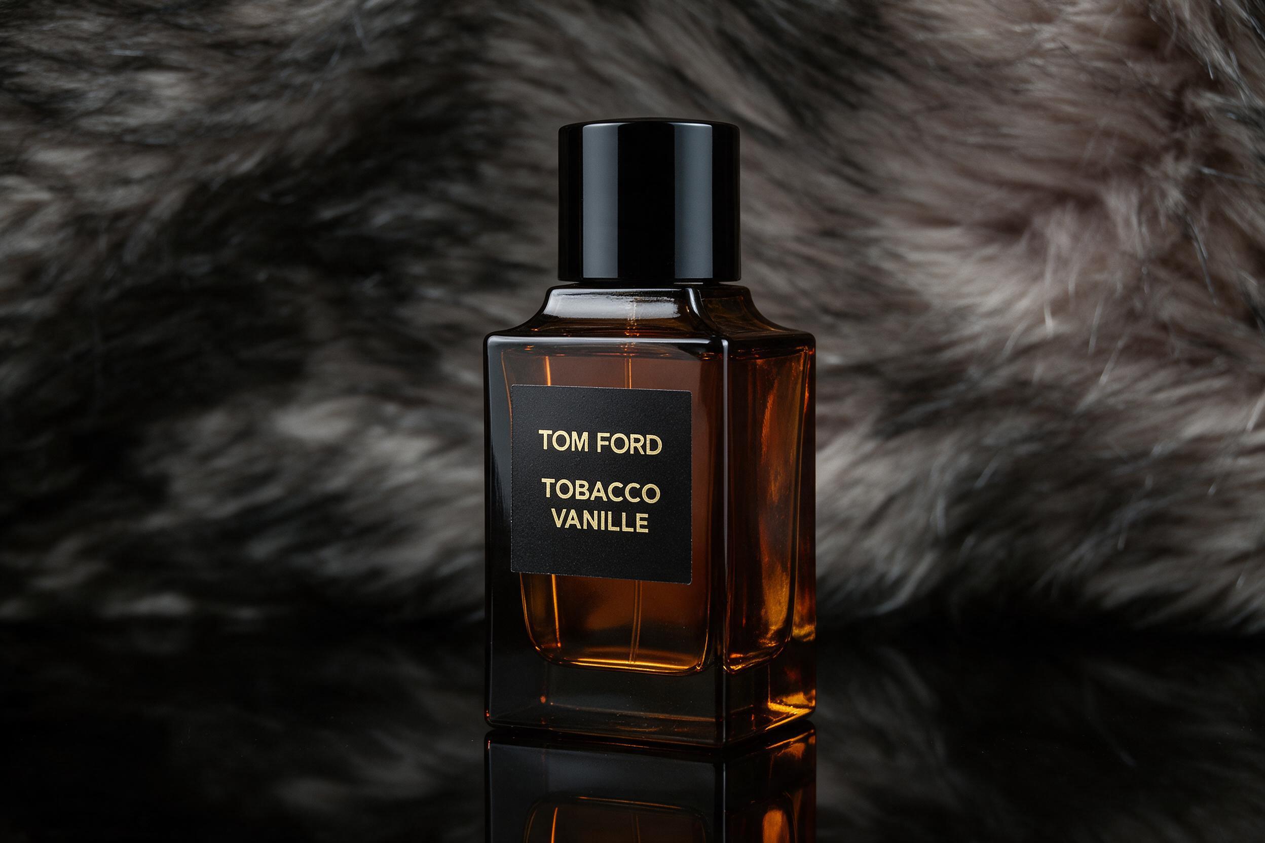 professional studio product photography of a Tom Ford Tobacco Vanille perfume bottle standing upright on a reflective bl
